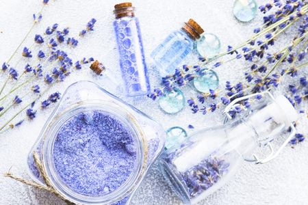 Spa and wellness setting with lavender flowers, sea salt, oil in a bottle, aroma candle on wooden white background closeupの写真素材