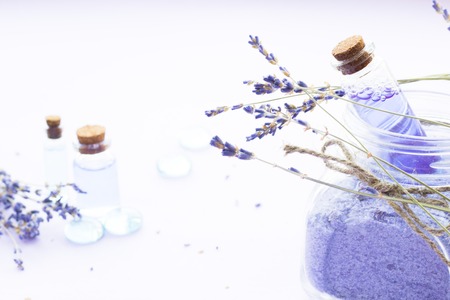 Spa and wellness setting with lavender flowers, sea salt, oil in a bottle, aroma candle on wooden white background closeupの写真素材