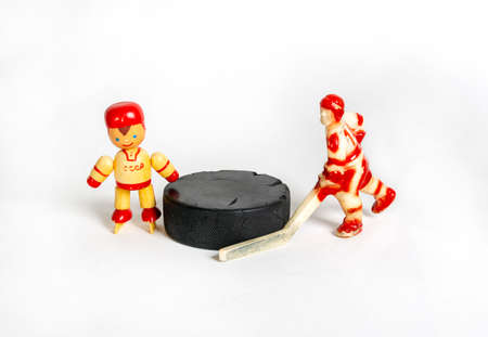 Hockey. Two red toy hockey players stand next to the puckの写真素材