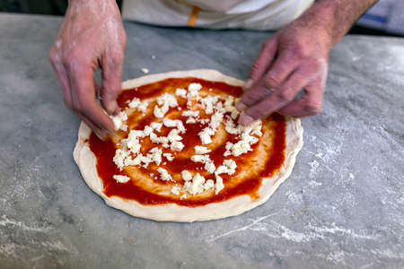 Cooking pizza. Pancake for pizza smeared with tomato sauce lies on the table.
