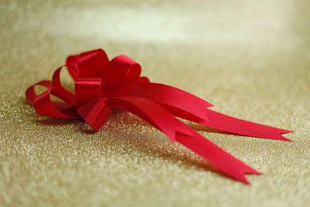 Christmas red bow on background in goldの写真素材