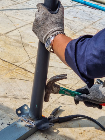 Mechanic repairing steel columns by welding and adjust the distance with a hammer amid the scorching...
