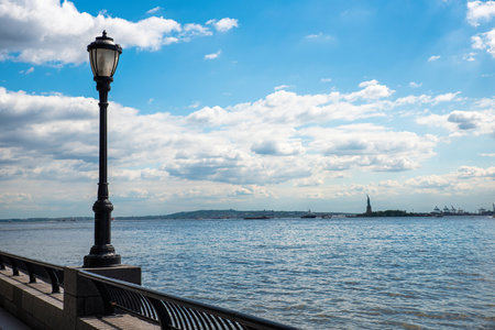 Lamp on the fence on the waterfront in New York, the Statue of Liberty is seen nearbyの写真素材