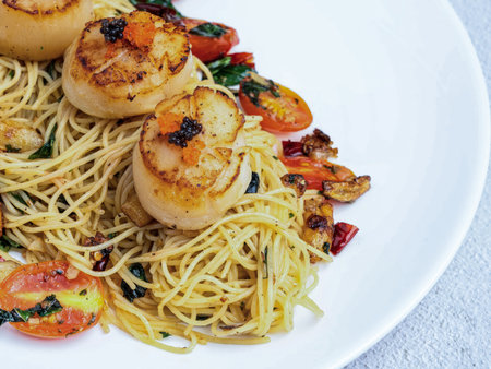 Spaghetti with grilled scallops, cherry tomatoes and basil.の写真素材