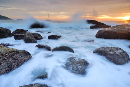 Sea waves lash line impact rock onthe beachの写真素材