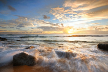 Sea waves lash line impact rock onthe beachの写真素材