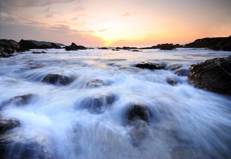 Sea waves lash line impact rock onthe beachの写真素材