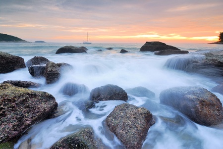 Sea waves lash line impact rock onthe beachの写真素材