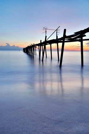 old wooden bridge in the sea with sunsetの写真素材