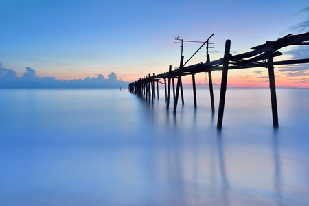 old wooden bridge in the sea with sunset