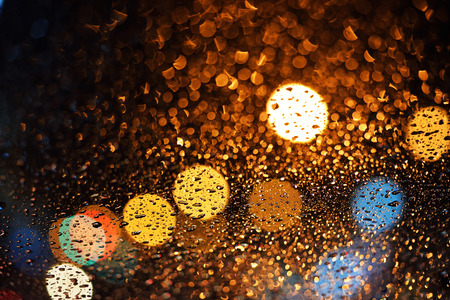 drops of rain on window with bokeh lights abstract 