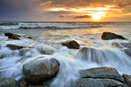 Sea waves lash line impact rock on the beachの写真素材