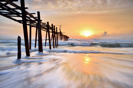 old wooden bridge in to the sea sunset on the beachの写真素材