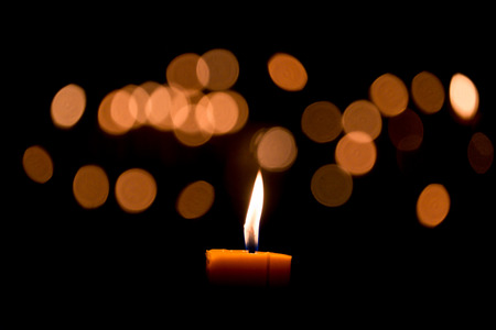 Candle flame light at night with bokeh on dark backgroundの写真素材