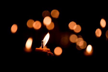 Candle flame light at night with bokeh on dark backgroundの写真素材