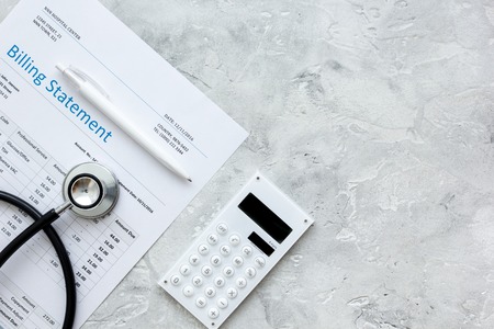 Stethoscope, billing statement for doctor's work in medical center on stone background top view space for textの写真素材