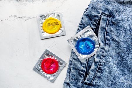 male contraception and jeans with condom on white table background top viewの写真素材