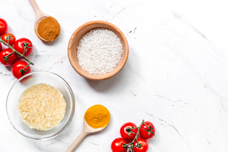 cooking paella with vegetables and rice ingredients on white kitchen desk background top view mockupの写真素材