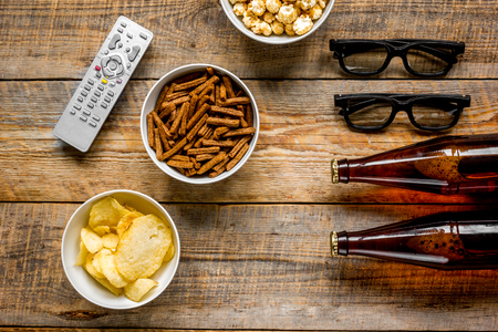 film whatching party with beer, crumbs, chips and pop corn on wooden background top view mockupの写真素材