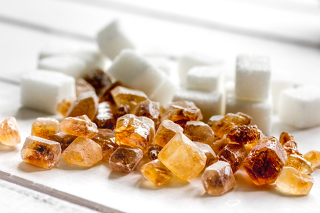 lumps of white and brown sugar on white wooden table backgroundの写真素材