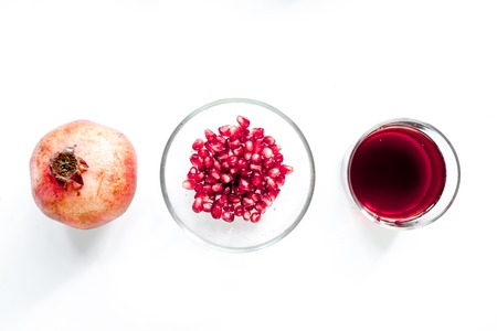 summer dessert with red juice and cut pomegranate on white background top view