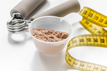 nutrition for workout with protein cocktail powder, measure tape and bars on white table backgroundの写真素材