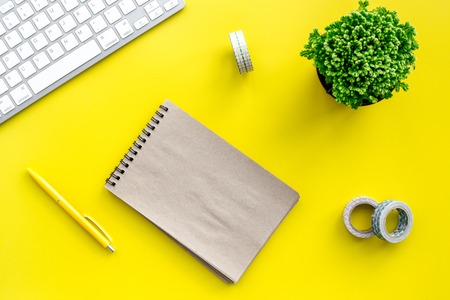 summer office desk at home with flowers, notebook and keyboard on yellow background top view space for textの写真素材