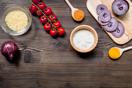 paella ingredients with rice, salt, spices and tomatoes on wooden kitchen table background top view mockupの写真素材