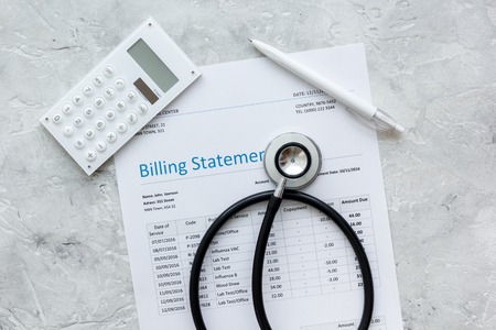 health care costs with billing statement, stethoscope and calculator on stone table top viewの写真素材