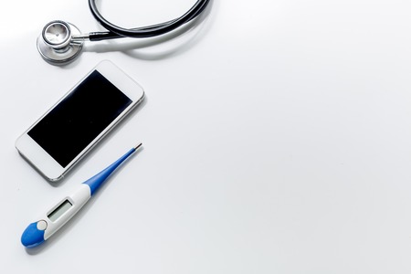 calling doctor set with mobile and stethoscope on white desk background top view mockup