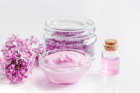 lilac cosmetics with flowers and spa set on white table backgroundの写真素材