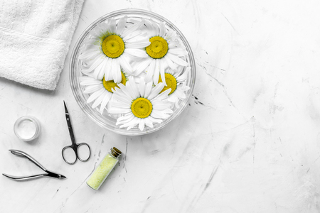 natural cosmetics with bowl of chamomiles and tools for manicure on white textural background top view space for text.の写真素材
