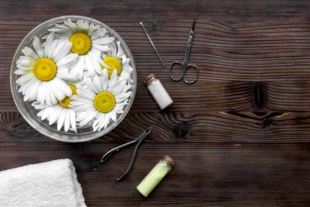 preparation for manicure with chamomile on dark wooden background top view space for text.の写真素材