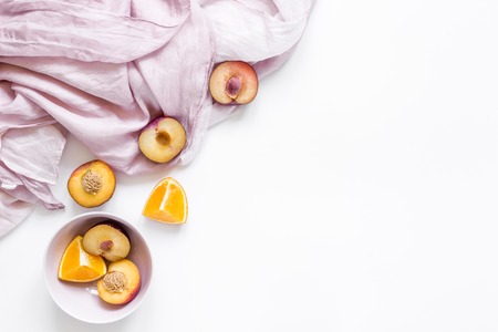 woman summer breackfast with orange and peach fruits and pink fabric on white desk background flat lay mockupの写真素材