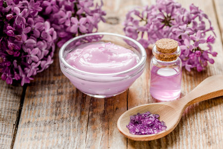 take bath with lilac cosmetic spa set and blossom on woode table backgroundの写真素材