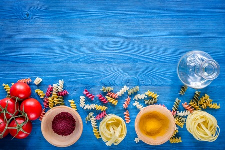 Food ingredients for Italian pasta on blue wooden desk background top view copyspace.
