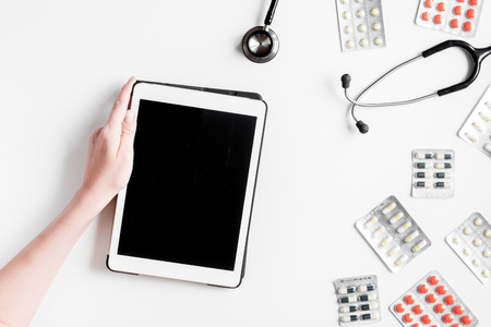 doctor's work desk in hospital with stethoscope and tablet on white background top view mockupの写真素材