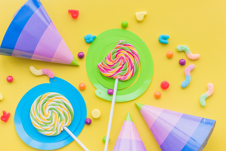 Lollipops and party hats for happy birthday on yellow background top view.の写真素材