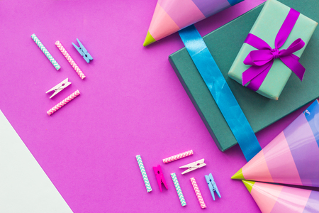 Birthday wrapped gifts and party hats on purple background top view copyspace.の写真素材