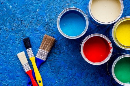 Colorful paints and brushes on blue wooden desk background top view.の写真素材