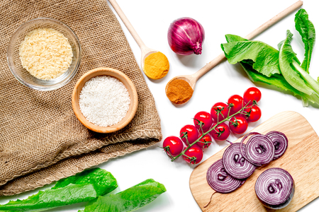 rice, spices and vegetables for paella on white desk background top viewの写真素材