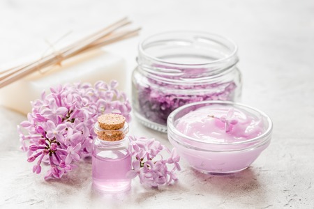 spa cosmetic set with lilac flowers stone desk backgroundの写真素材