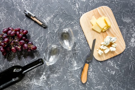 Bottle of red wine with cheese and grape aperitive on grey stone table background top viewの写真素材