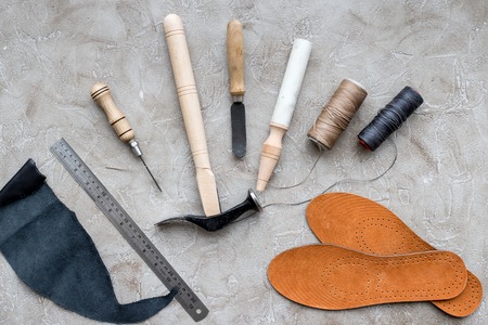 Set of cobbler tools on grey stone desk background top viewの写真素材