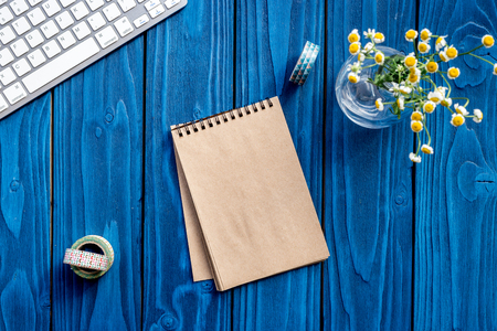 colorful work space with keyboard, notebook and flowers for home office blue wooden background top view mockupの写真素材