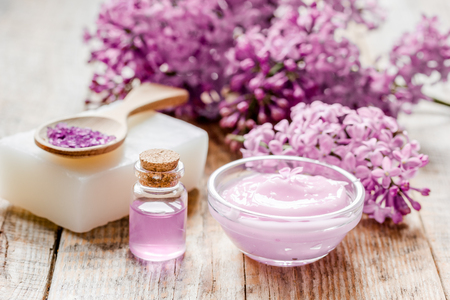 organic salt, cream, extract in lilac cosmetic set with flowers on wooden table backgroundの写真素材