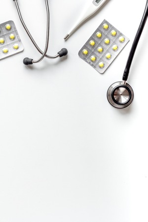 Medical equipment with stethoscope and pills in doctors office on white desk background top view mock-upの写真素材