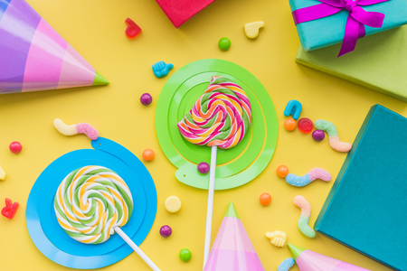 Lollipops and party hats for happy birthday on yellow background top viewの写真素材