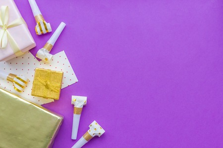 Birthday concept with gifts, greeting cards and party whistles on violet background top view copyspaceの写真素材