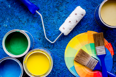 Colorful paints and brushes on blue wooden desk background top viewの写真素材